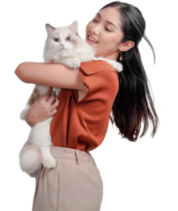 Femme souriante tenant un chat Ragdoll blanc et beige dans ses bras.